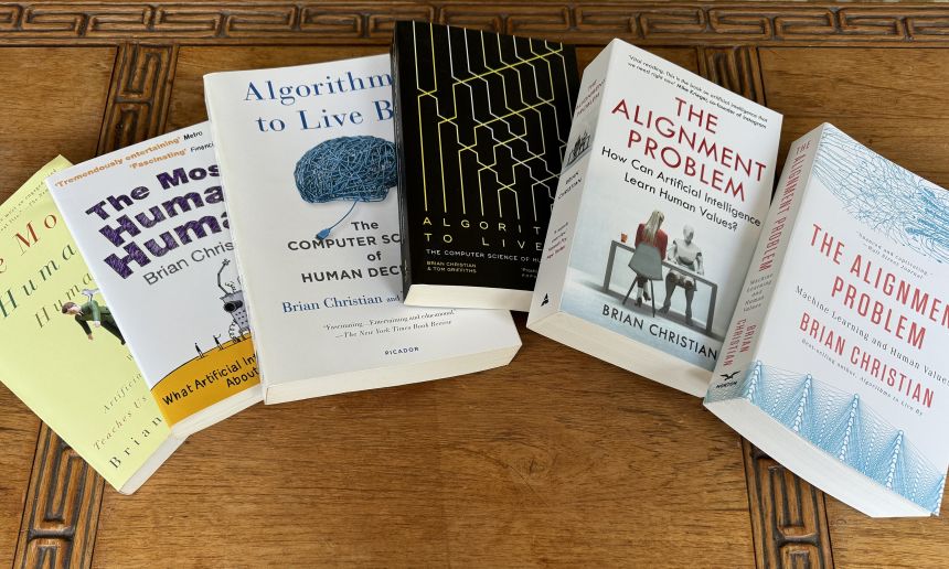 Five paperback books spread across a table. The titles are The Most Human Human, Algorithms to Live By, and The Alignment Problem.